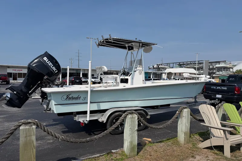 Slide: The Image of 2021 Intruder 23 boat with Suzuki outboard motor on a trailer in a marina parking lot. - 7