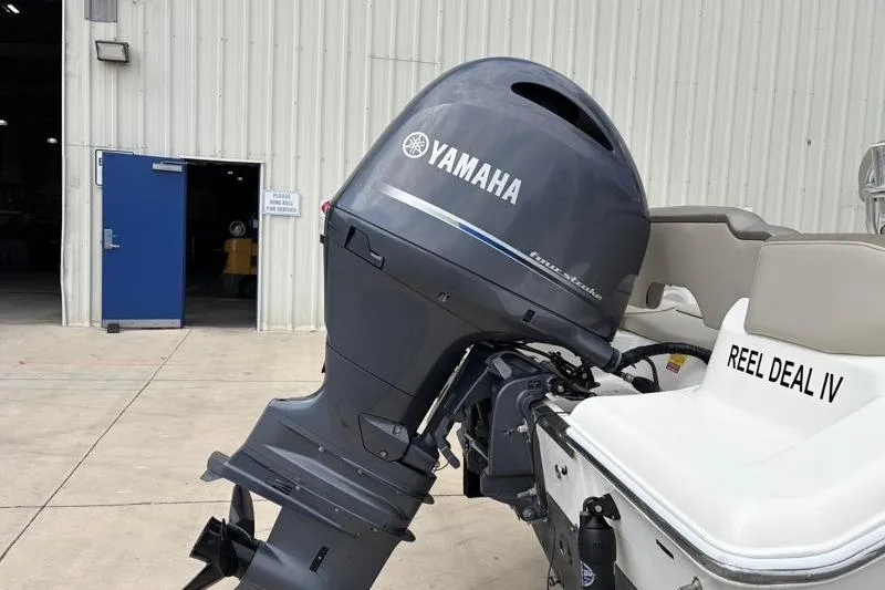 Slide: The Image of 2023 Key West 203 FS boat with Yamaha outboard motor, docked near a warehouse. - 11