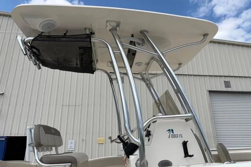 Slide: The Image of 2023 Key West 203 FS boat with T-top and seating, docked near a warehouse. - 13