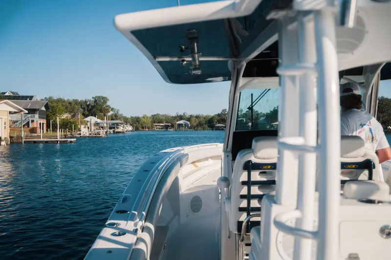 Slide: The Image of 2019 HCB 42 Siesta boat cruising on a serene waterway near waterfront homes. - 2