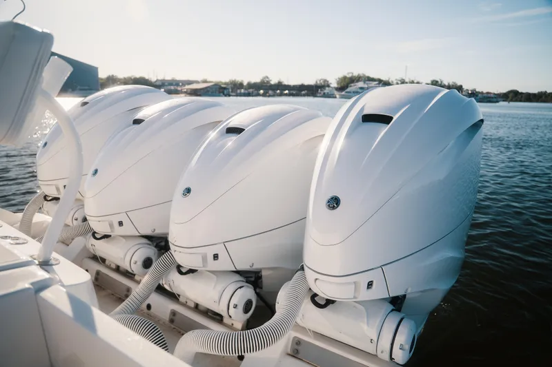 Slide: The Image of Four powerful outboard engines on a 2019 HCB 42 Siesta boat, docked on calm water. - 33