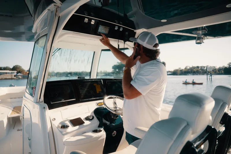 Slide: The Image of Man operating 2019 HCB 42 Siesta boat's control panel on a sunny day. - 9