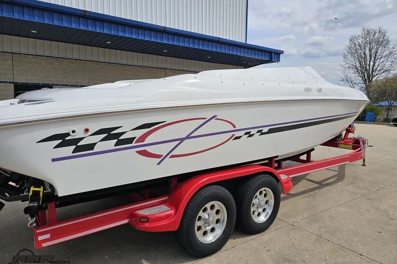 Slide: The Image of 1999 Baja 272 speedboat on red trailer, parked outdoors near a building. - 10