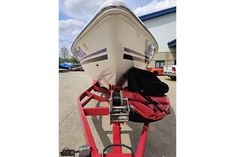 Slide: The Image of 1999 Baja 272 boat on red trailer, parked outdoors near a building. - 16