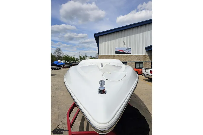 Slide: The Image of 1999 Baja 272 boat on trailer, parked outside a building under a cloudy sky. - 17