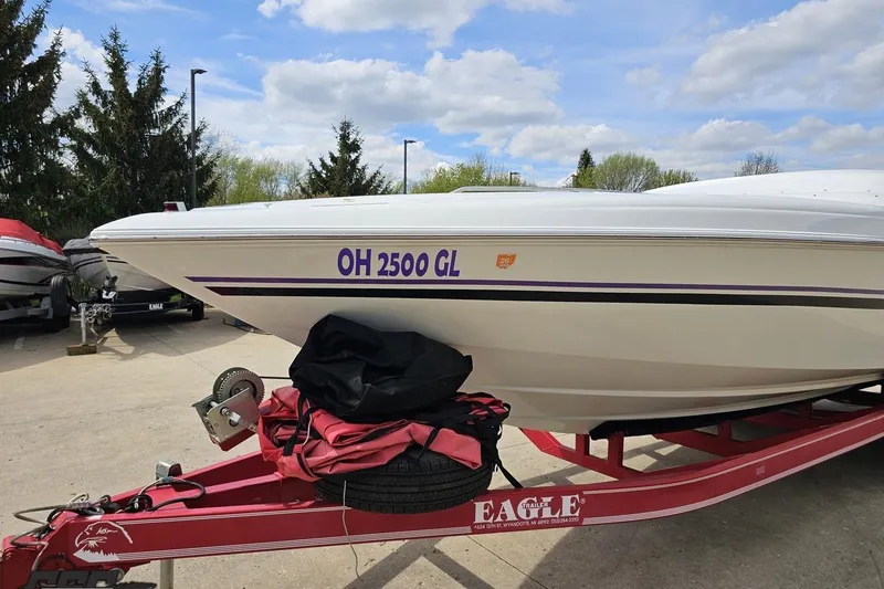 Slide: The Image of 1999 Baja 272 boat on red trailer, parked outdoors under a cloudy sky. - 19