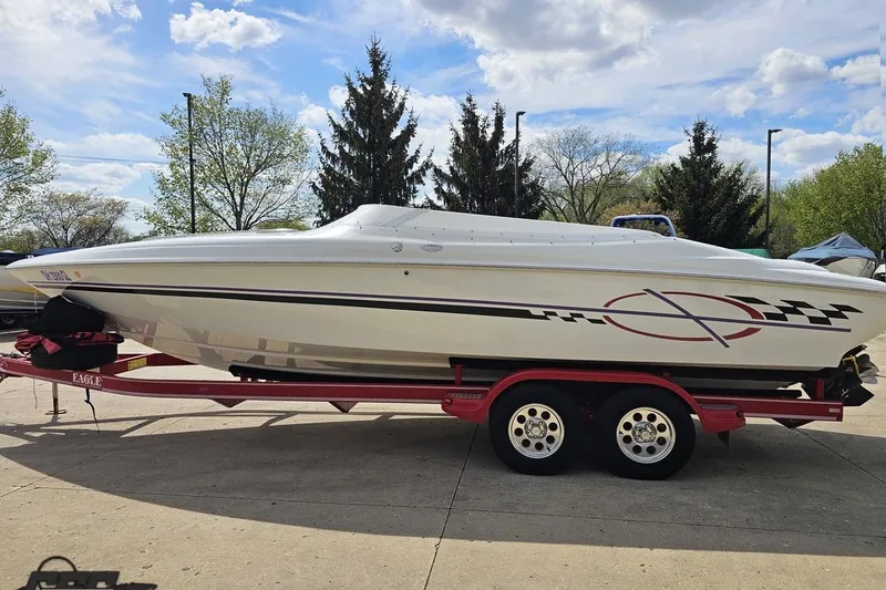 Slide: The Image of 1999 Baja 272 speedboat on red trailer, parked outdoors under a cloudy sky. - 21