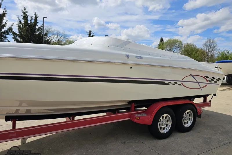 Slide: The Image of 1999 Baja 272 speedboat on red trailer, parked outdoors under a cloudy sky. - 22