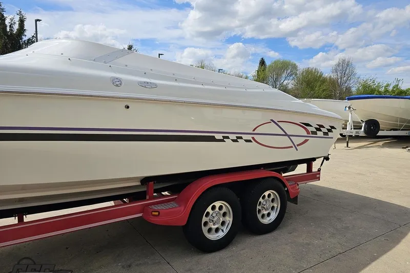 Slide: The Image of 1999 Baja 272 boat on red trailer, parked outdoors under a cloudy sky. - 24