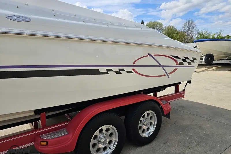 Slide: The Image of 1999 Baja 272 boat on red trailer, featuring sleek graphics and parked outdoors. - 25