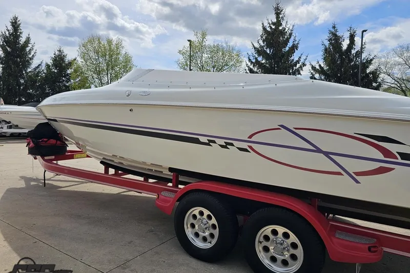 Slide: The Image of 1999 Baja 272 speedboat on red trailer, parked outdoors under cloudy sky. - 27