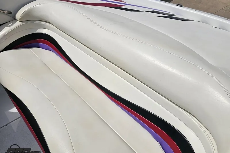 Slide: The Image of White leather seating with colorful accents in a 1999 Baja 272 boat interior. - 48