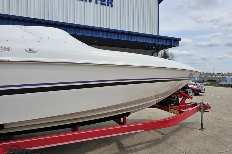 Slide: The Image of 1999 Baja 272 boat on red trailer outside a building under a cloudy sky. - 5