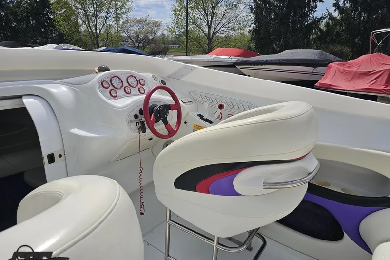 Slide: The Image of Interior of a 1999 Baja 272 boat with white and purple seating, red steering wheel. - 50