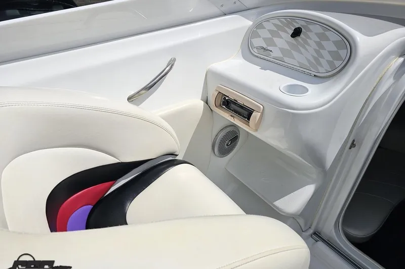 Slide: The Image of Interior of a 1999 Baja 272 boat featuring white seating and dashboard details. - 54