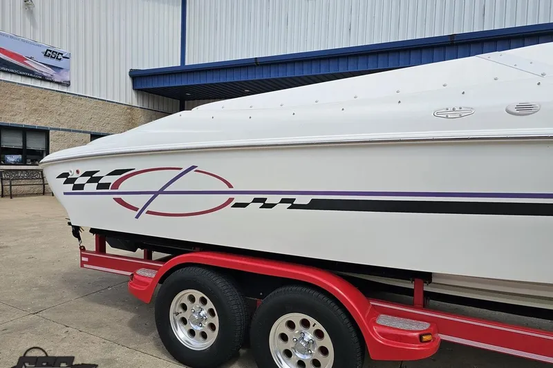 Slide: The Image of 1999 Baja 272 boat on red trailer, parked outside a building. - 6