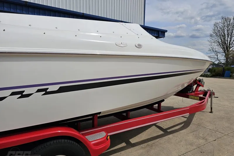 Slide: The Image of 1999 Baja 272 boat on red trailer, featuring sleek white hull with black and purple accents. - 7