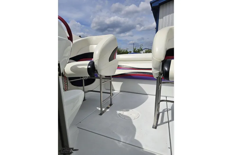 Slide: The Image of 1999 Baja 272 boat interior with white and purple seating under a cloudy sky. - 79