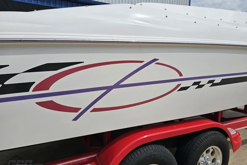 Slide: The Image of 1999 Baja 272 boat with colorful graphics on a red trailer. - 9