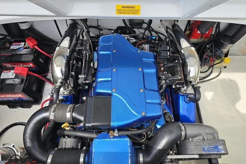 Slide: The Image of Engine compartment of a 1999 Baja 272 boat with blue engine cover and Duralast batteries. - 92