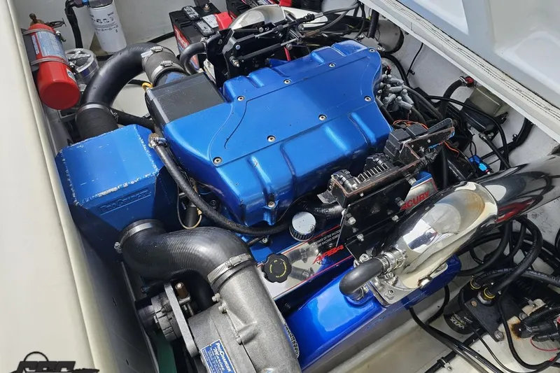 Slide: The Image of Engine compartment of a 1999 Baja 272 boat, featuring a blue engine and various components. - 93