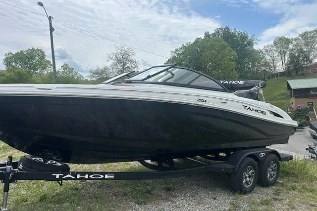 The Image of 2026 Tahoe 210 S boat on trailer, parked outdoors with trees in background. - 0