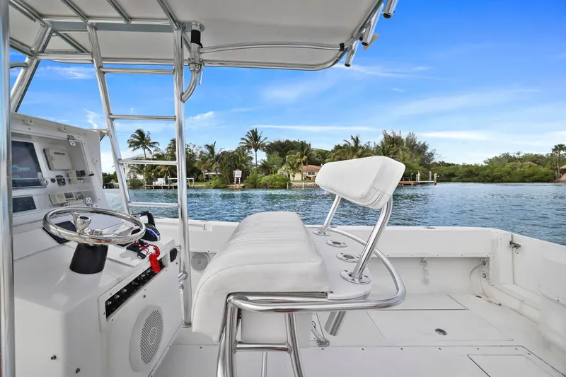 Slide: The Image of 2002 Contender 31 Open boat interior with helm, overlooking serene waterfront and lush greenery. - 22