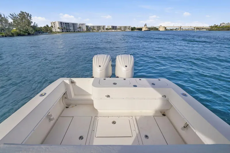 Slide: The Image of 2002 Contender 31 Open boat with dual engines on calm water, near coastal buildings. - 32