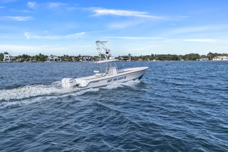 Slide: The Image of 2002 Contender 31 Open boat cruising on a scenic waterway with coastal homes in the background. - 8