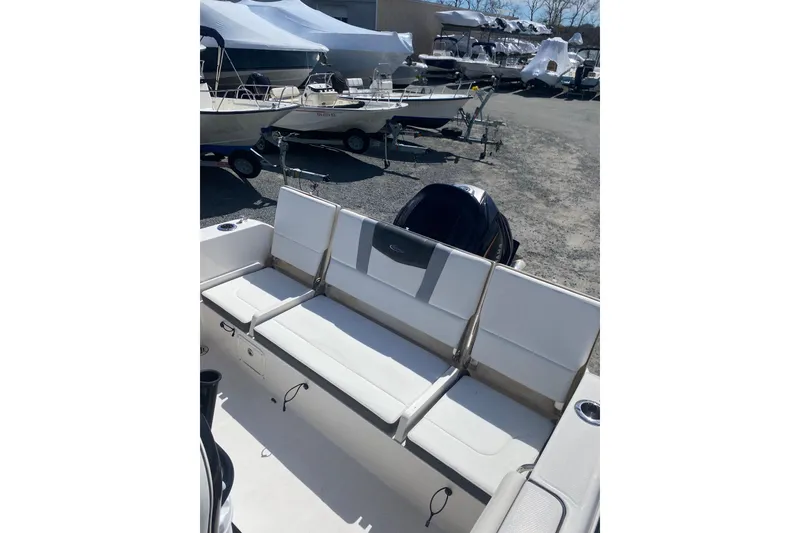Slide: The Image of 2023 Robalo R230 Center Console boat with white seating, parked outdoors. - 12