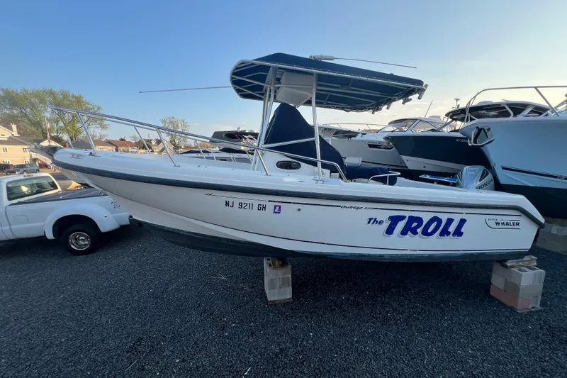 The Image of 1998 Boston Whaler Outrage 23 boat named "The Troll" on display, parked on blocks. - 1