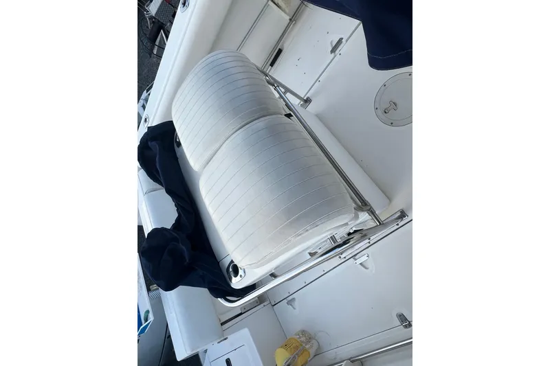 Slide: The Image of 1998 Boston Whaler Outrage 23 boat interior with white cushioned seating. - 19