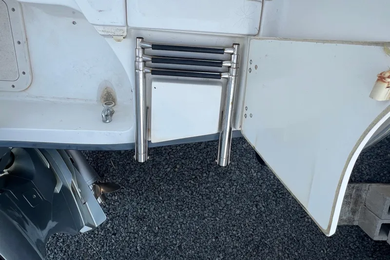 Slide: The Image of 1998 Boston Whaler Outrage 23 boat ladder and motor detail on gravel surface. - 20