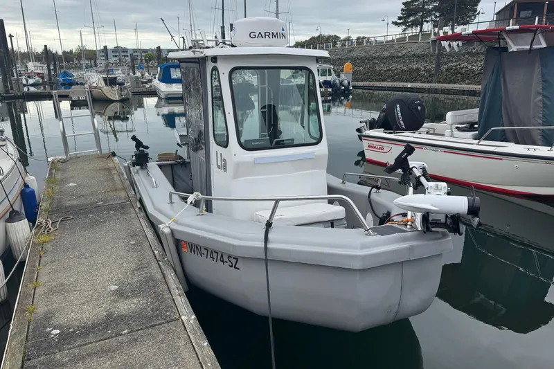 Slide: The Image of 2022 Bullfrog 17ft Pilot House boat docked in a marina with other vessels. - 2