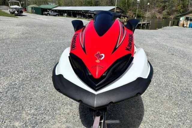 Slide: The Image of 2012 Kawasaki Jetski Ultra LX in red and white, parked on gravel near a dock. - 8