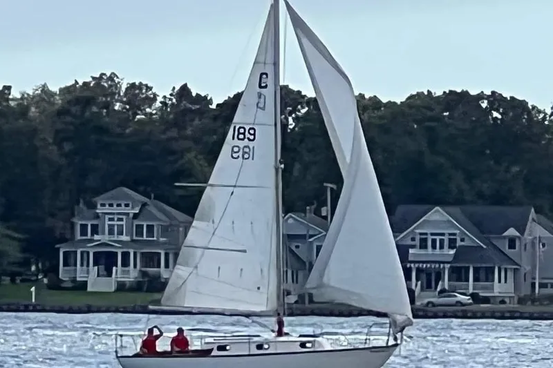 The Image of 1989 Cape Dory 27 sailboat cruising near waterfront homes. - 0