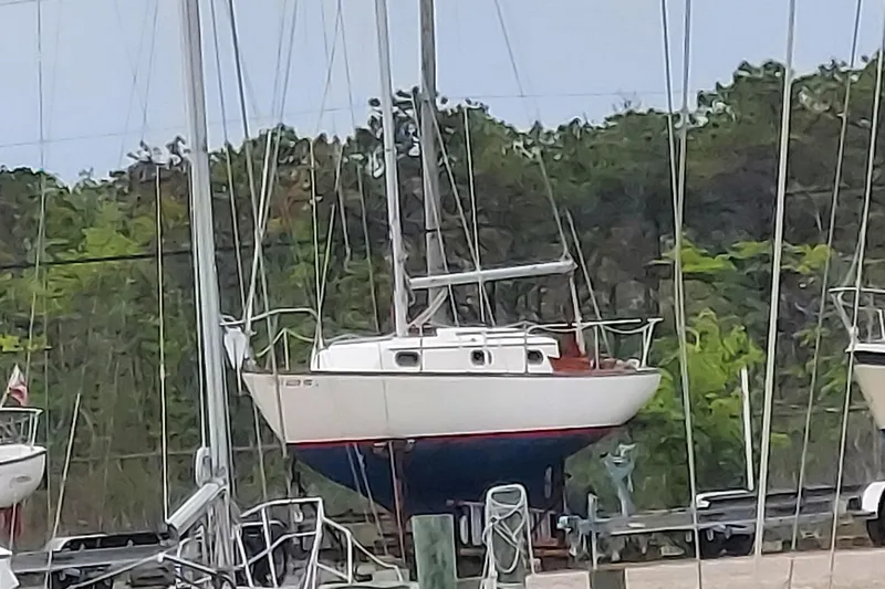 Slide: The Image of 1989 Cape Dory 27 sailboat on land, surrounded by trees and other boats. - 4