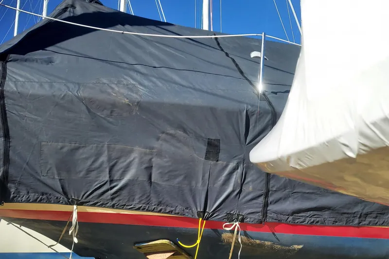 Slide: The Image of 1989 Cape Dory 27 sailboat covered, docked under clear blue sky. - 9