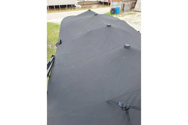 Slide: The Image of Black cover on 2022 Starcraft SLS 1 DL boat, secured with straps, outdoor setting. - 15