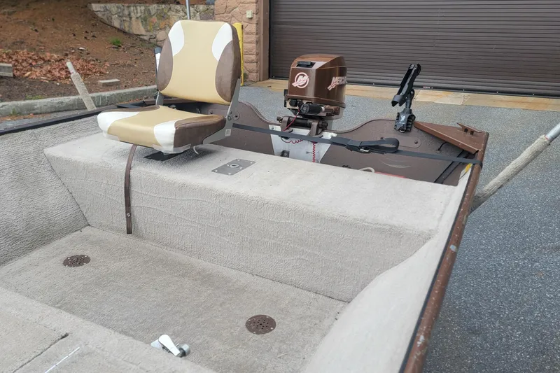 Slide: The Image of 2001 Nova NV JWMV1650SF boat interior with seat and motor, parked on pavement. - 8