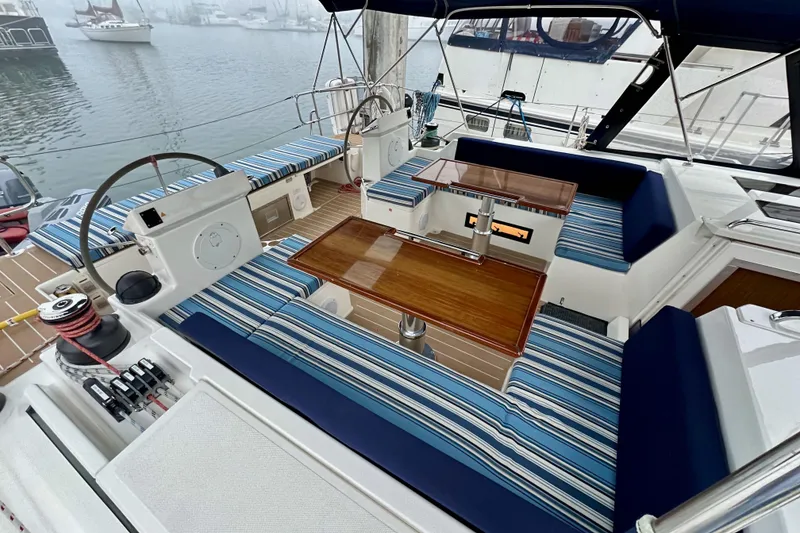 Slide: The Image of 2020 Bavaria C50 yacht cockpit with striped seating and wooden table, docked in a marina. - 27