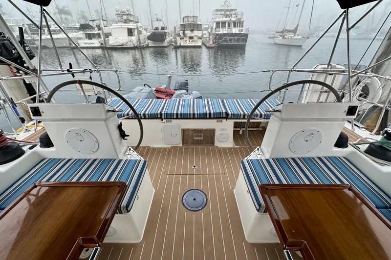 Slide: The Image of Cockpit of 2020 Bavaria C50 yacht with striped seating, dual steering wheels, and marina view. - 29