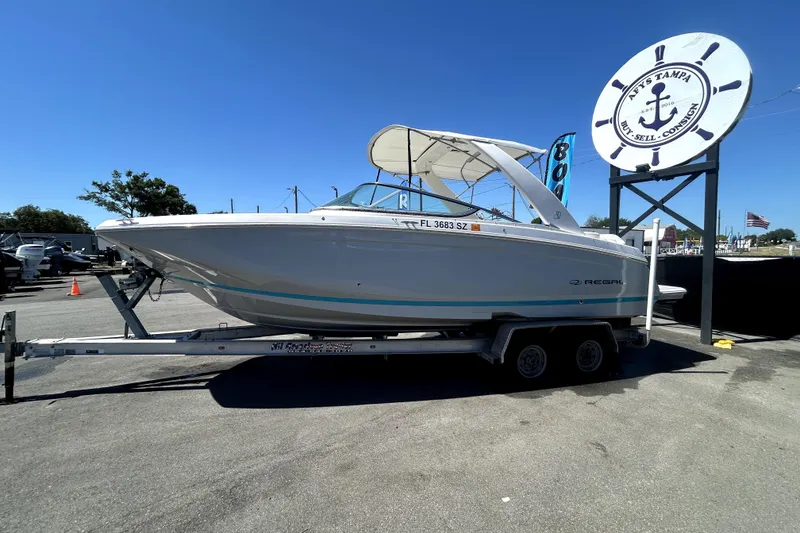 Slide: The Image of 2021 Regal 26 FasDeck boat on trailer at a marina under clear blue sky. - 11