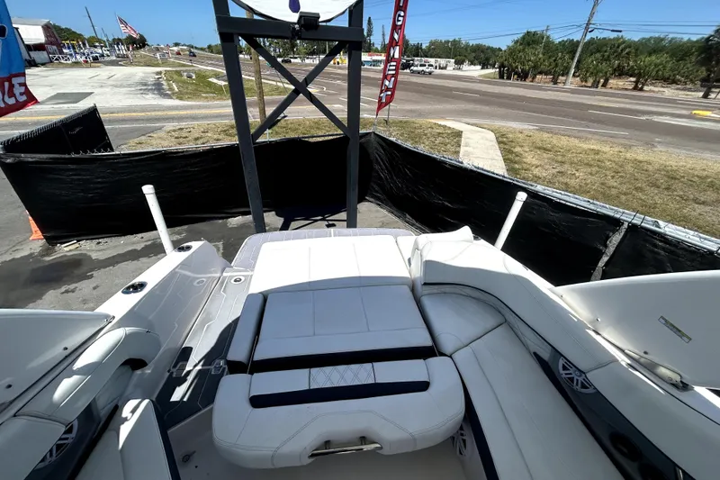 Slide: The Image of 2021 Regal 26 FasDeck boat interior with white seating, parked near a road. - 18