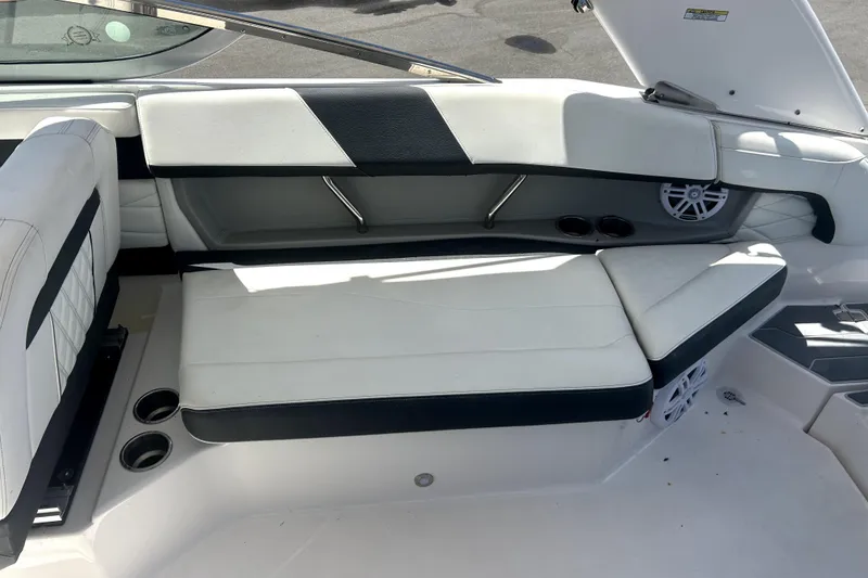 Slide: The Image of 2021 Regal 26 FasDeck boat interior with white and black seating, cup holders, and speaker. - 50