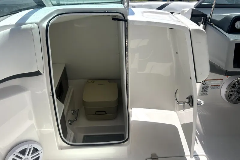 Slide: The Image of 2021 Regal 26 FasDeck boat interior with open door revealing compact restroom. - 55