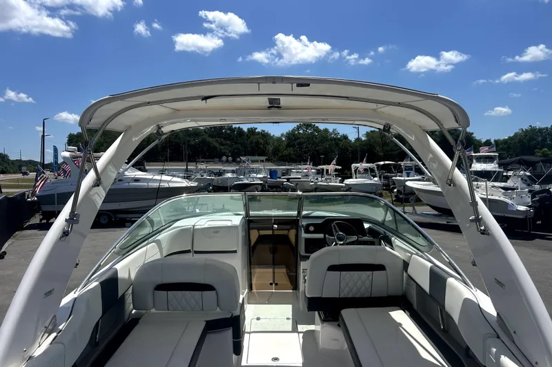 Slide: The Image of 2021 Regal 26 FasDeck boat interior with seating, steering wheel, and canopy under a clear blue sky. - 70