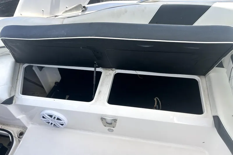 Slide: The Image of Open storage compartment on a 2021 Regal 26 FasDeck boat, featuring a speaker and cushioned seat. - 81