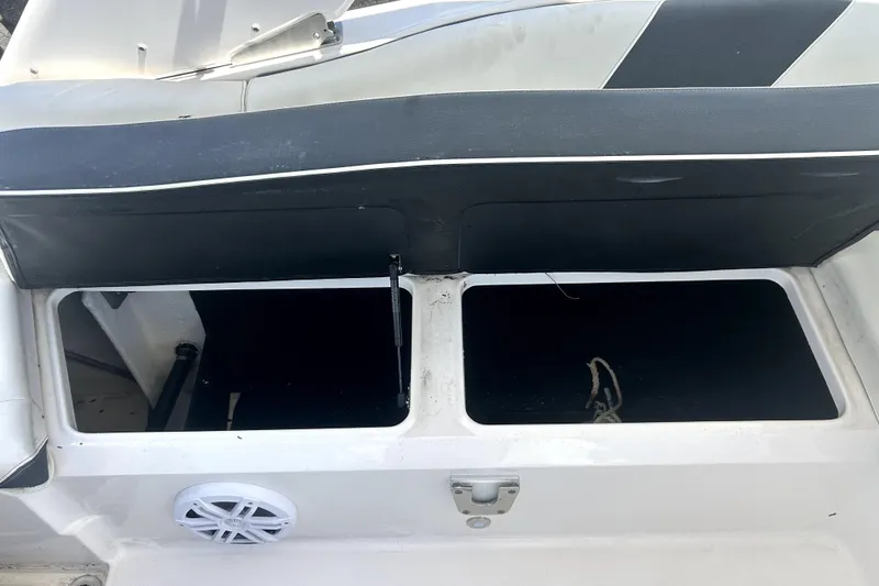 Slide: The Image of Open storage compartment on a 2021 Regal 26 FasDeck boat, featuring a speaker and latch. - 82