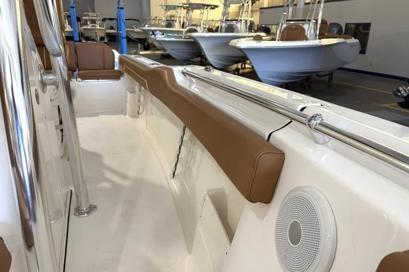 Slide: The Image of 2025 Key West 239 FS boat interior with brown seating and speaker, in showroom. - 10